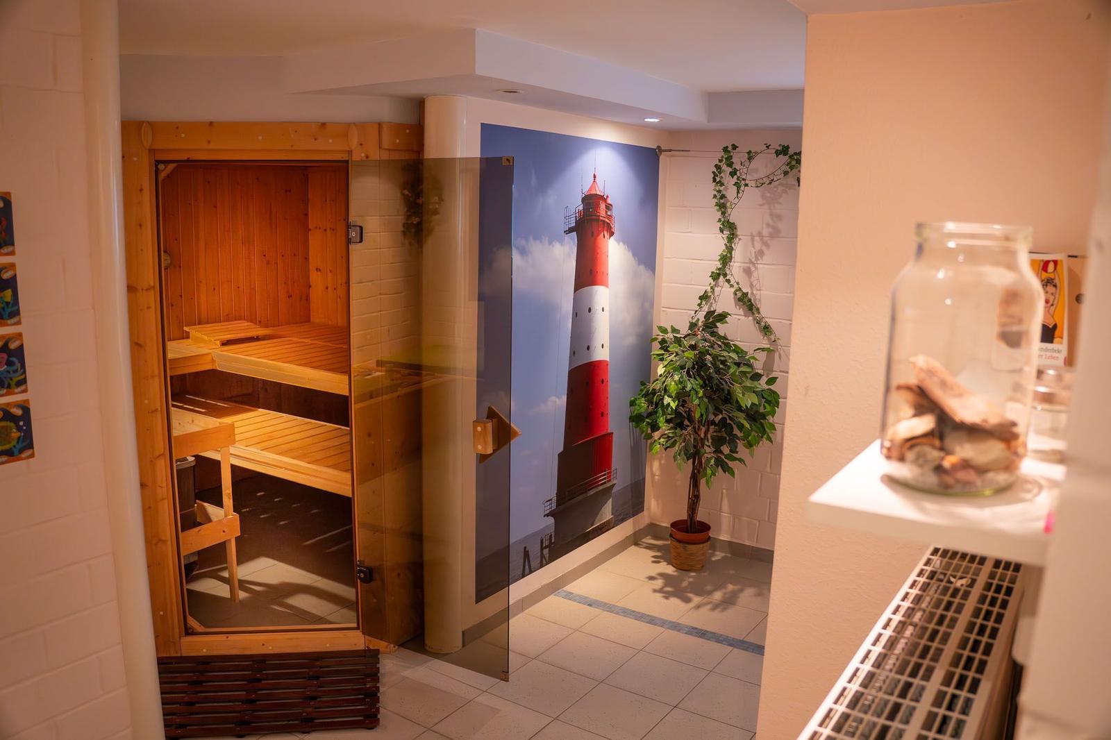 Sauna mit Holzbank und Wandbild eines Leuchtturms.