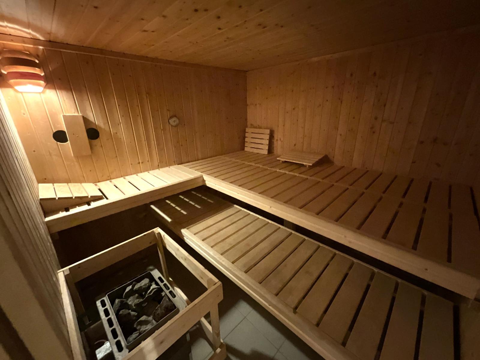 Holzsauna mit mehreren Sitzbänken und Steineinsatz.