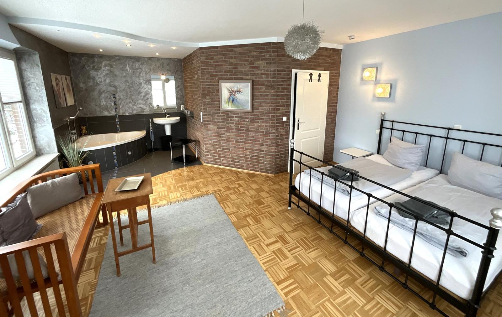 Schlafzimmer mit Doppelbett, Bad und Holzboden