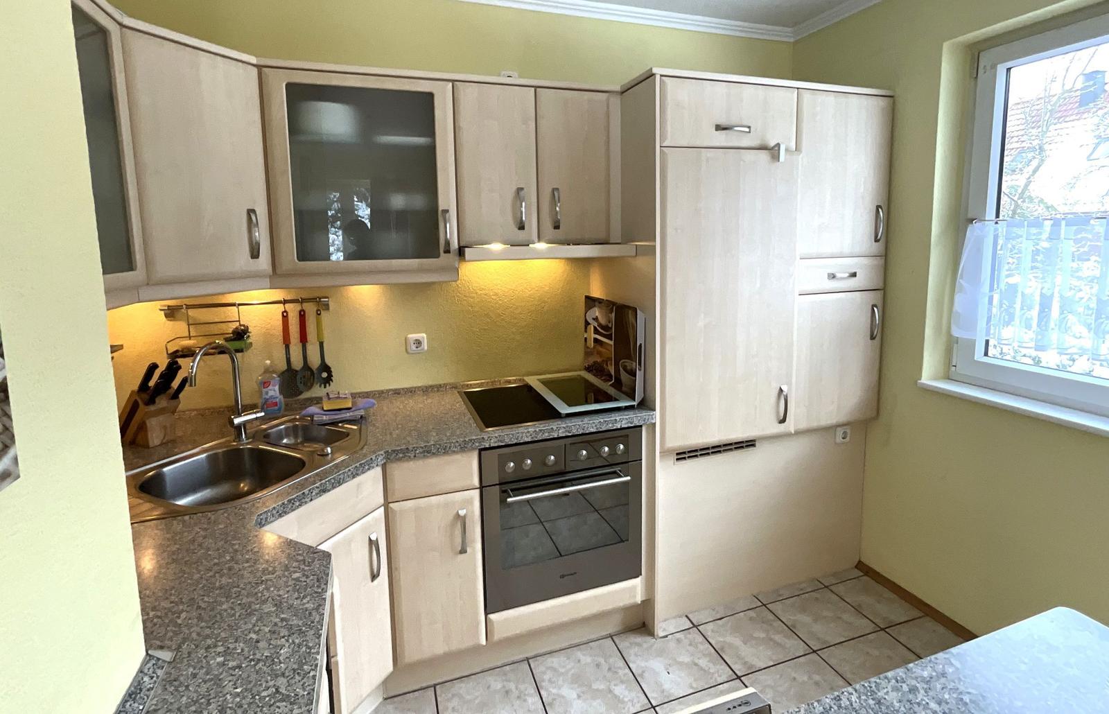 Küche mit hellen Schränken, Arbeitsplatte und Fenster