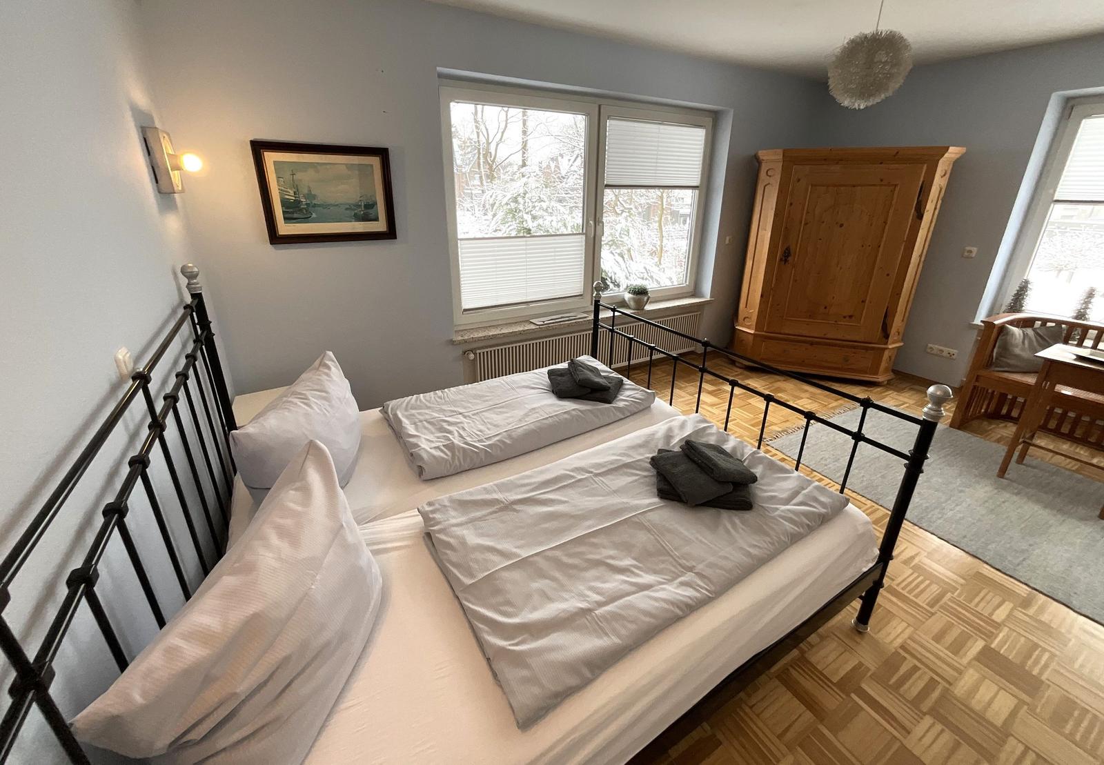 Zimmer mit Doppelbett, Holzmöbel und Fenster mit Blick auf Schnee.