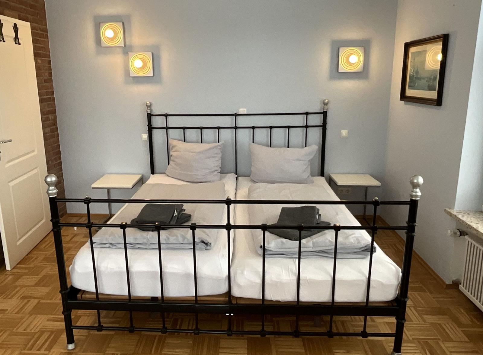 Zimmer mit Doppelbett, zwei Nachttischen und Wandlampen.