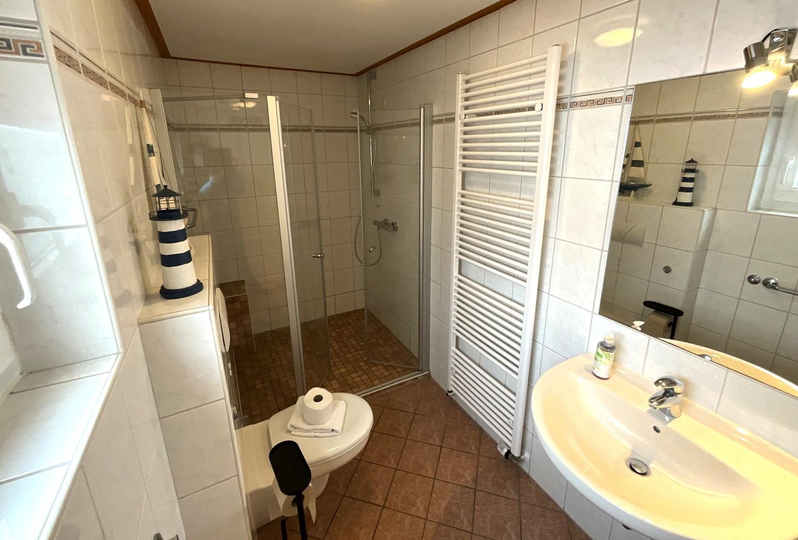 Badezimmer mit Dusche, Waschbecken und Heizkörper