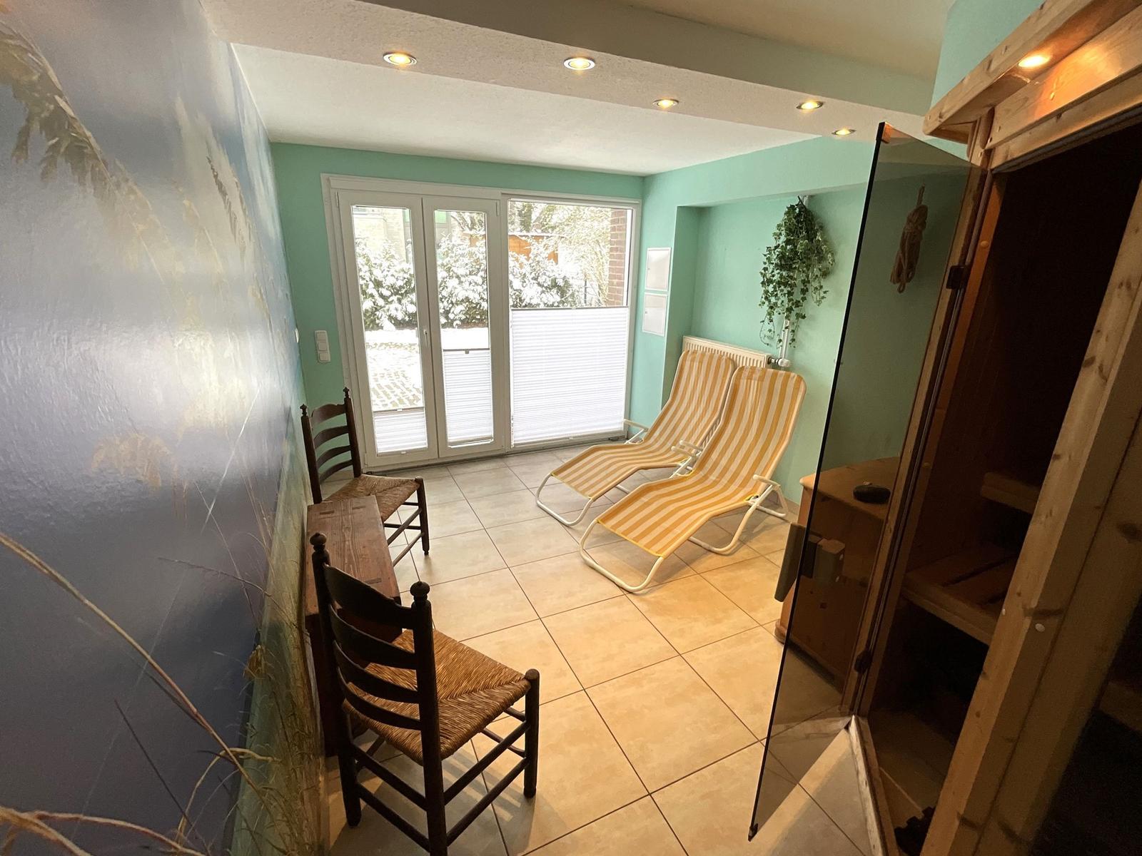 Raum mit Liegestühlen, Sauna und Terrassentür.