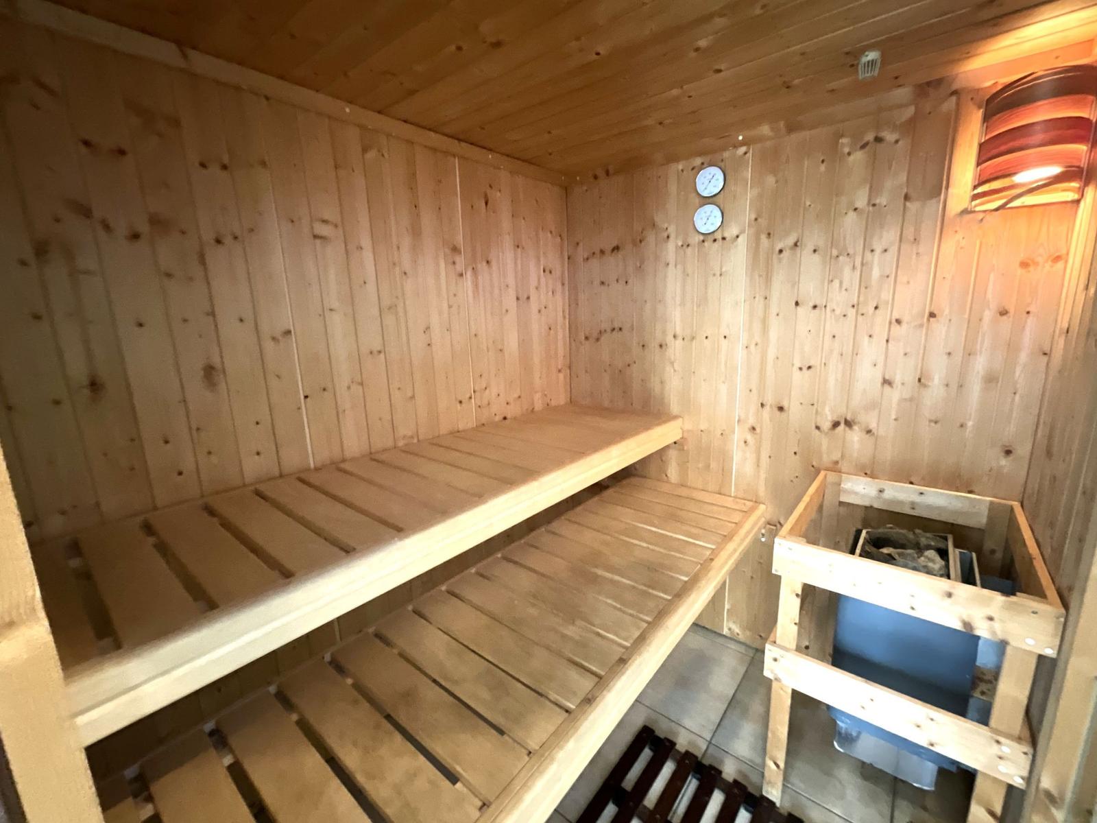 Sauna mit Holzbank, Holzwand und Heizung.