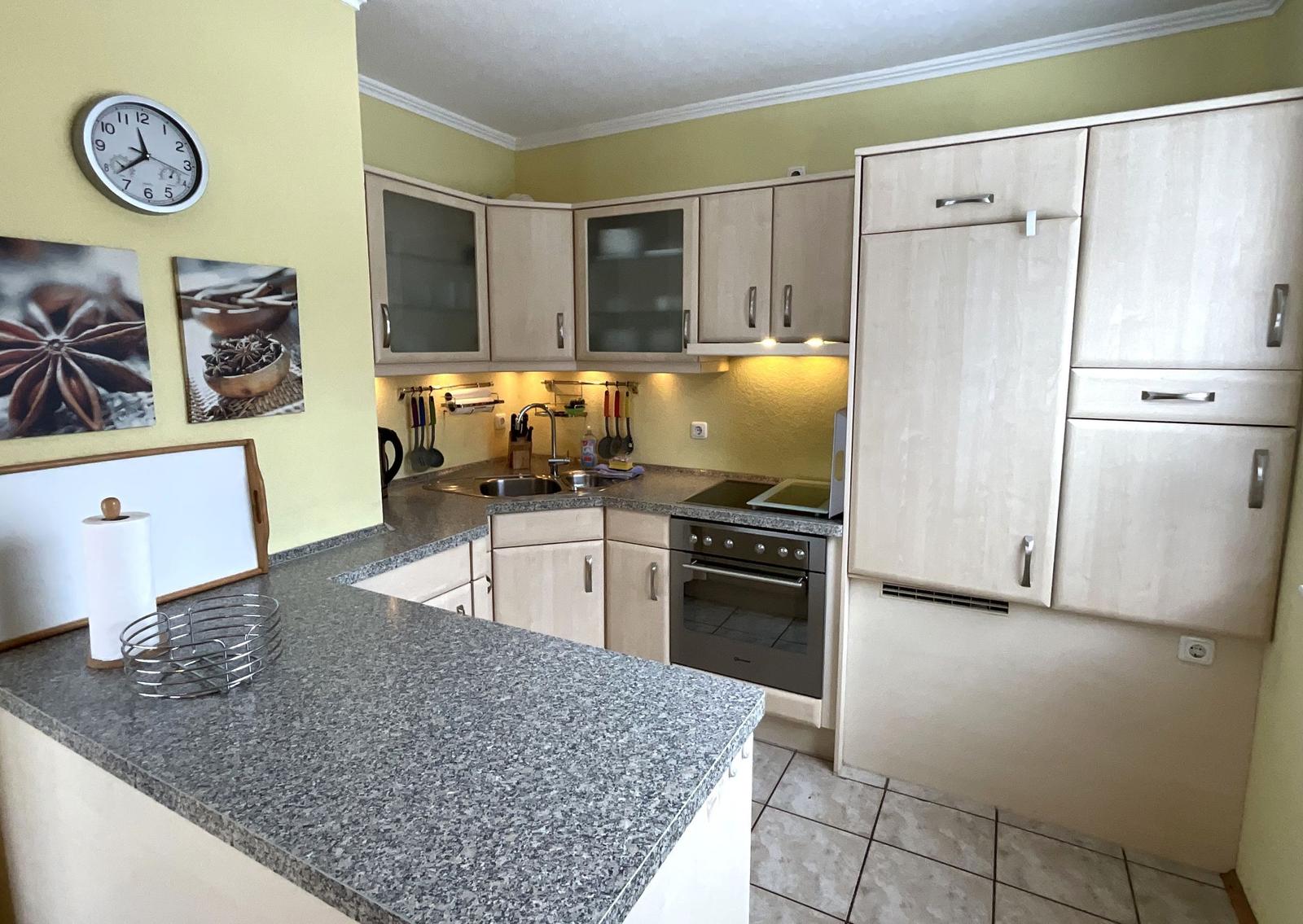 Küche mit hellen Schränken, Granitplatte und Edelstahlspüle.