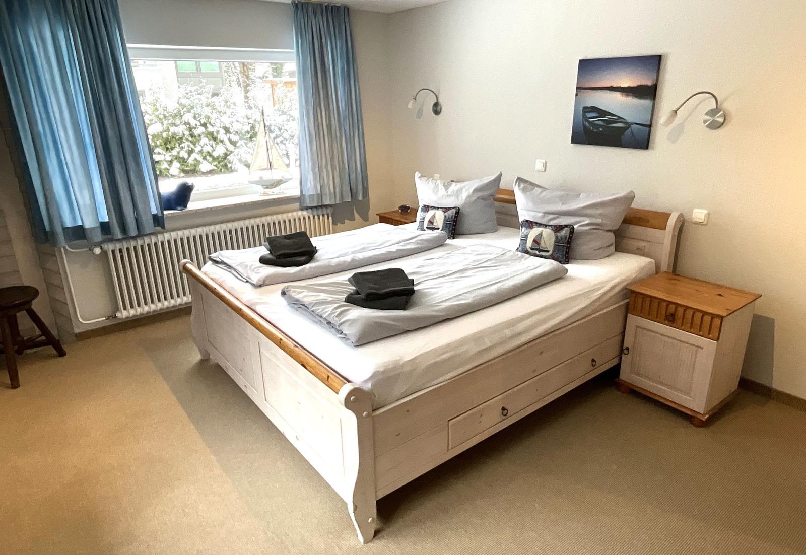 Schlafzimmer mit Doppelbett, Nachttisch und Fenster mit Blick.