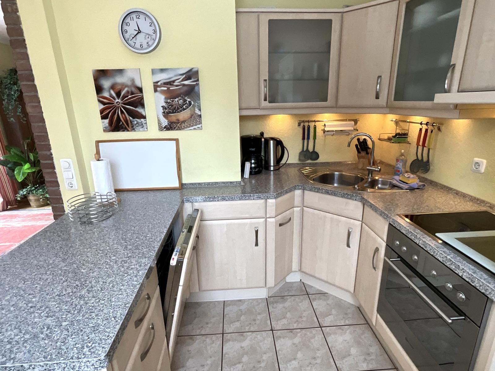 Küche mit hellen Schränken, Granitplatte und Edelstahlspüle.