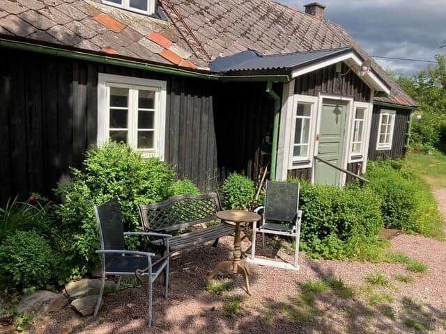 Schwarzes Holzhaus mit grüner Tür und Gartenmöbeln auf Kies