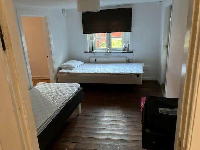 Zimmer mit zwei Betten, Holzboden und Fenster mit Rollladen.