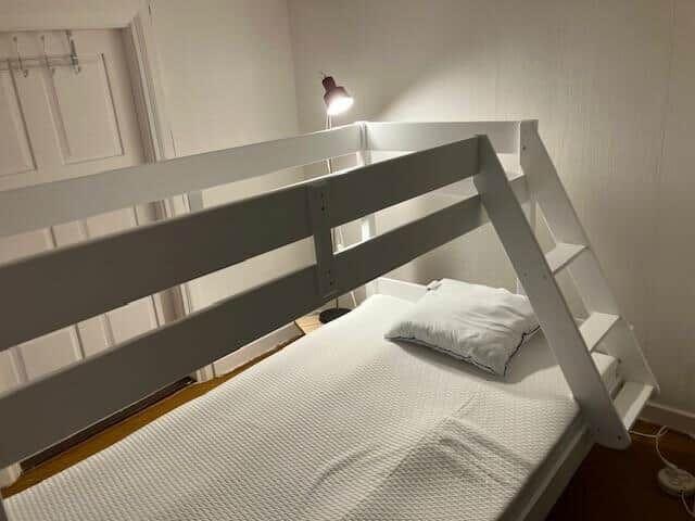 Hochbett mit Matratze und Kissen, integrierte Treppe und Stehlampe.