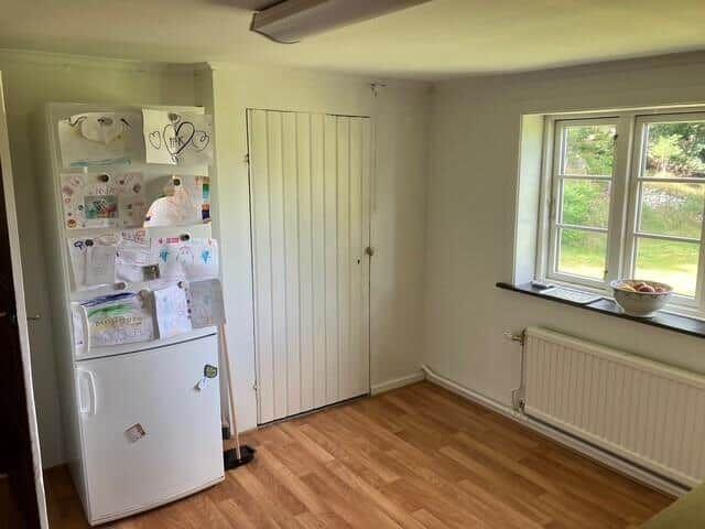 Küche mit Kühlschrank, Fenster und Holzboden