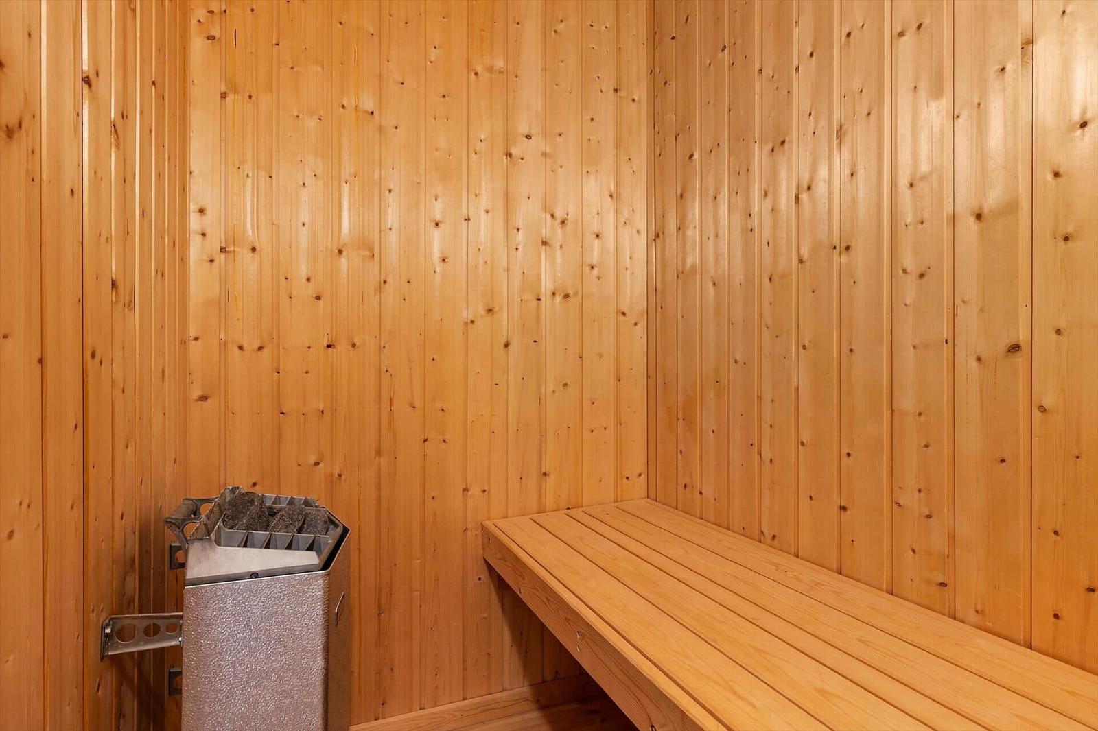 Sauna with wooden walls, bench, and heater.