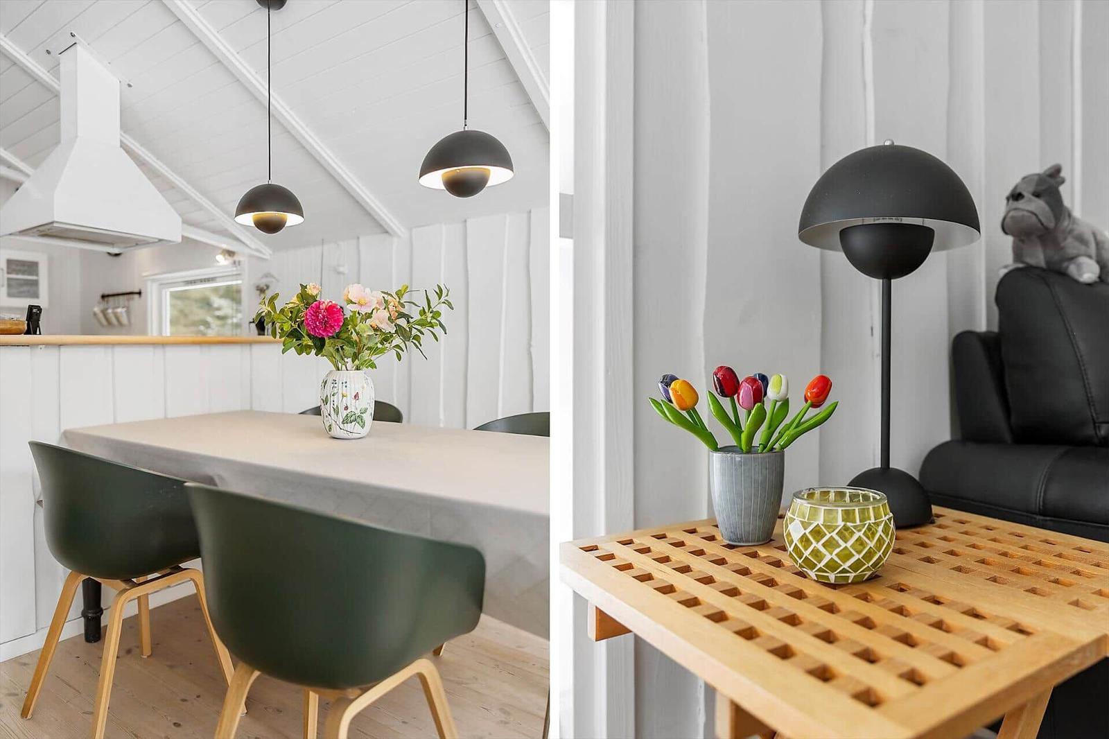 Dining area with table and chairs, living area with table, lamp, and flowers.