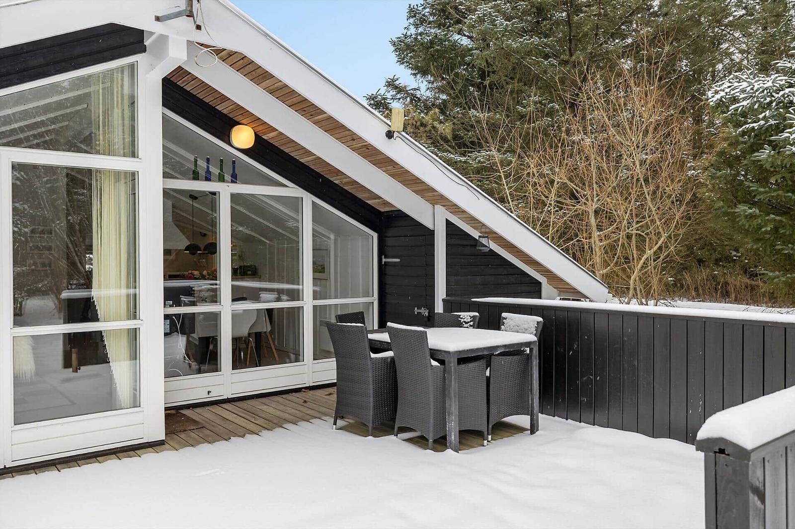 Snow-free outdoor area with table and chairs in front of a modern glass facade.