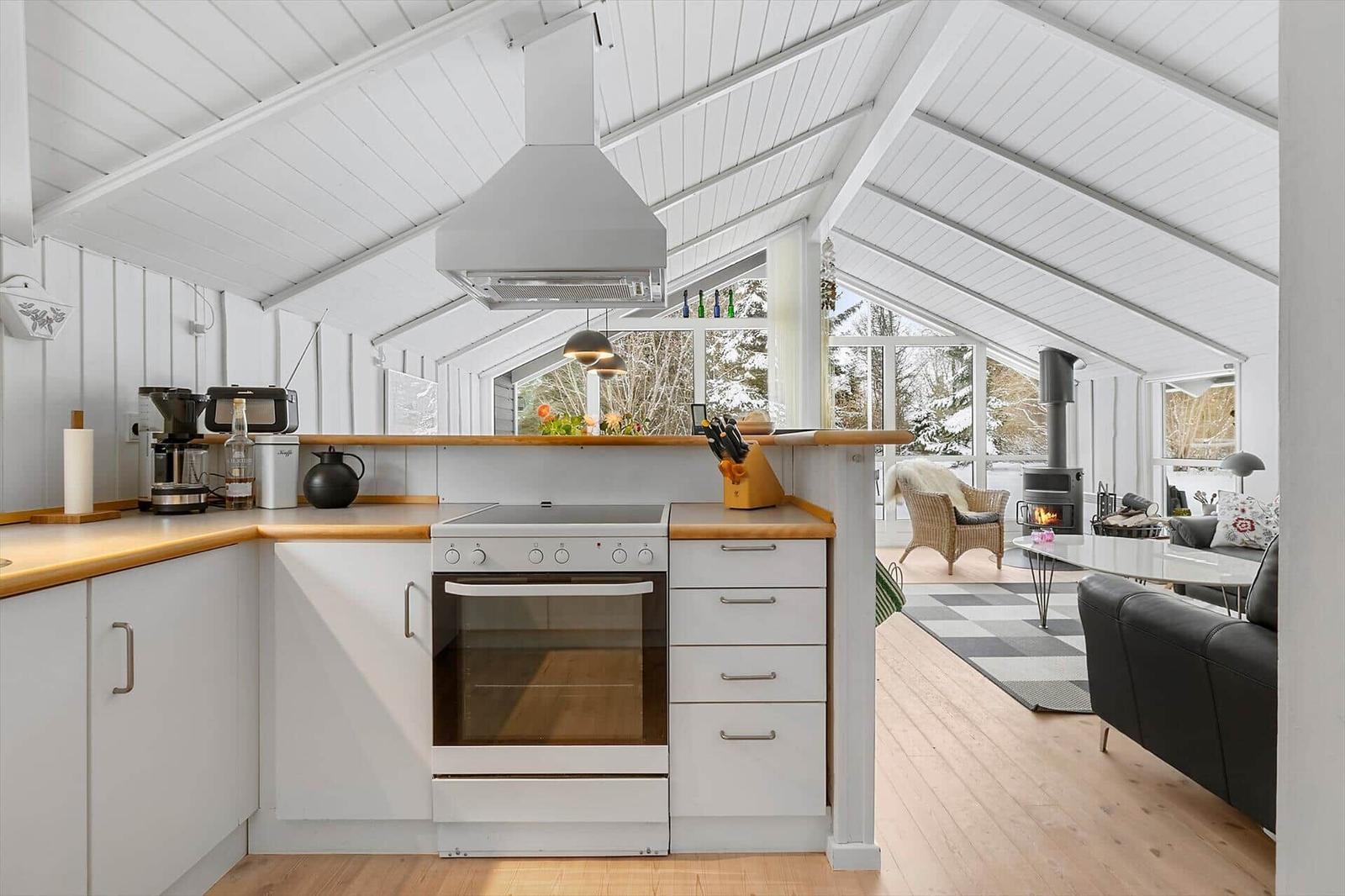 Kitchen with white countertop and wooden surface. View into living area with fireplace.