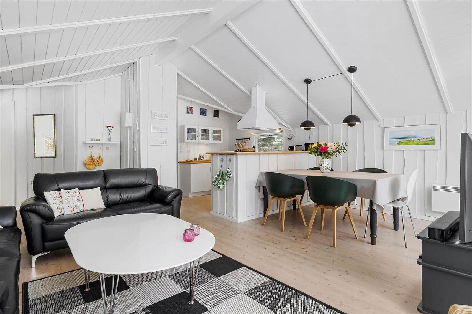 Living and dining area with sofa, dining table, and kitchen under high ceiling.