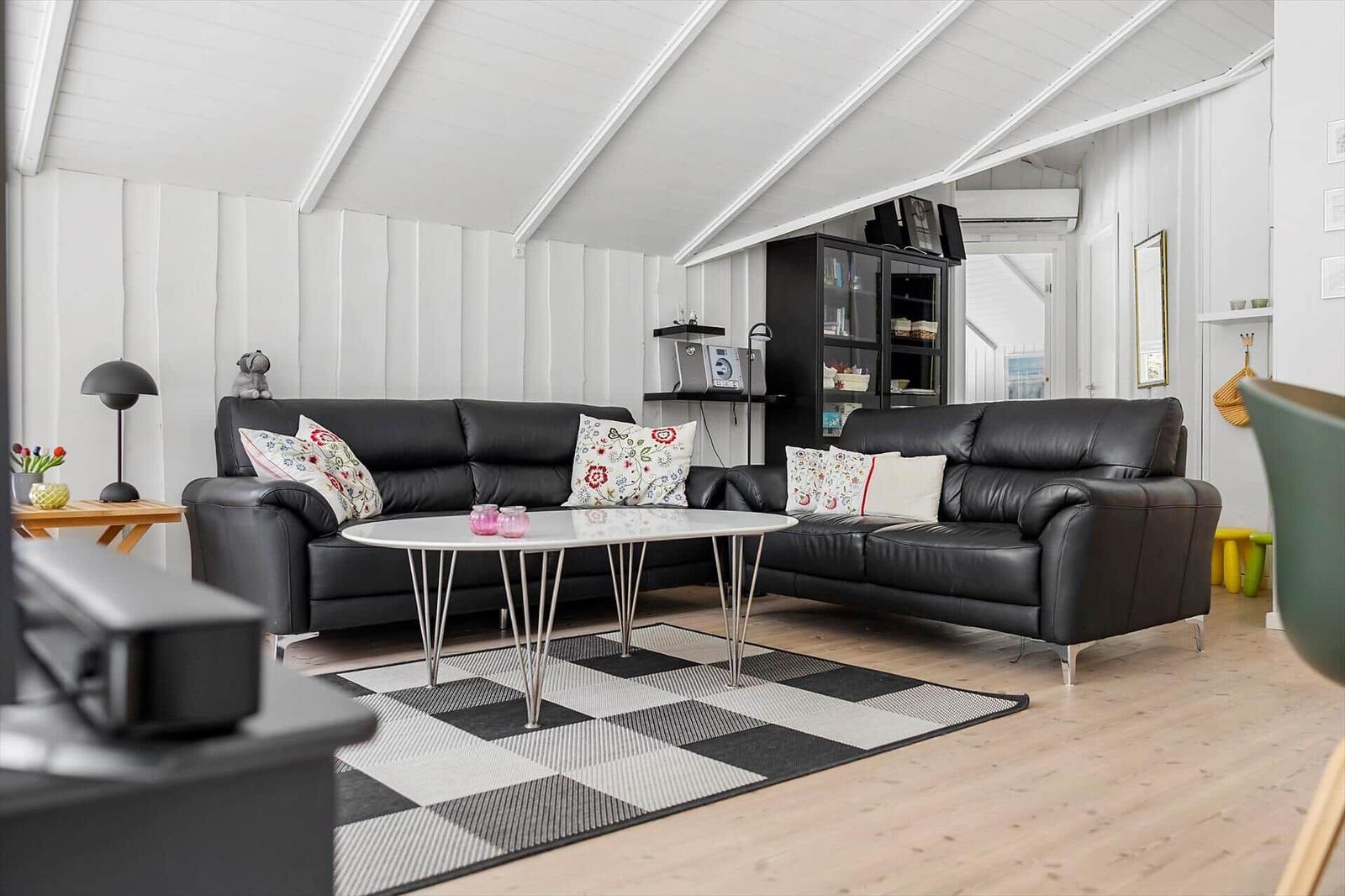 Two black leather sofas around a round table with a black-and-white rug.