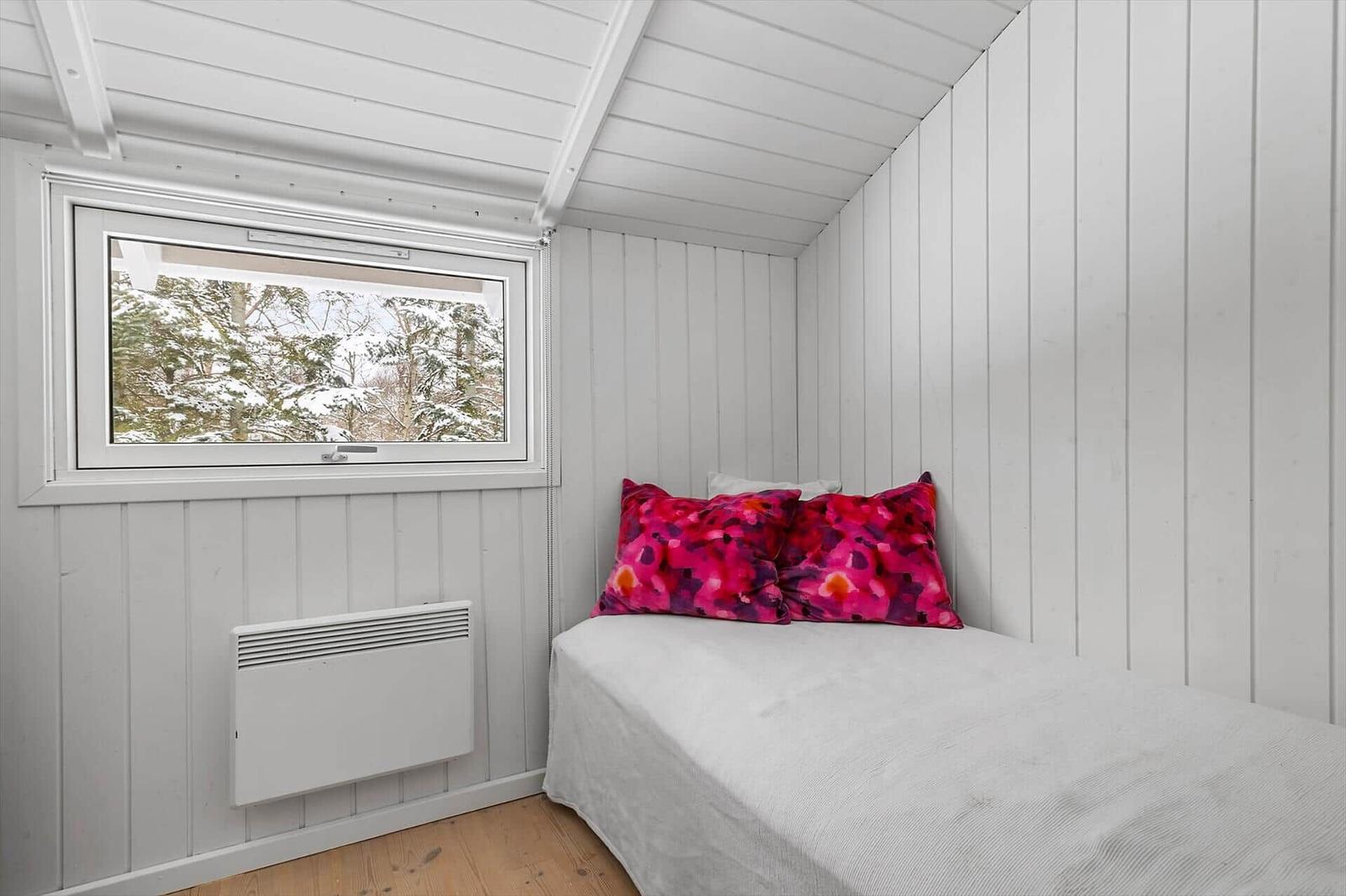 Bedroom with bed, window, and heater on the wall.