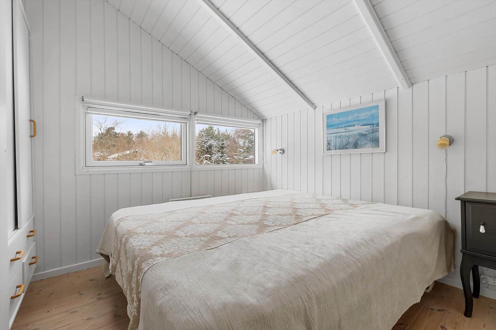 Bedroom with sloped ceiling, windows, and bed.