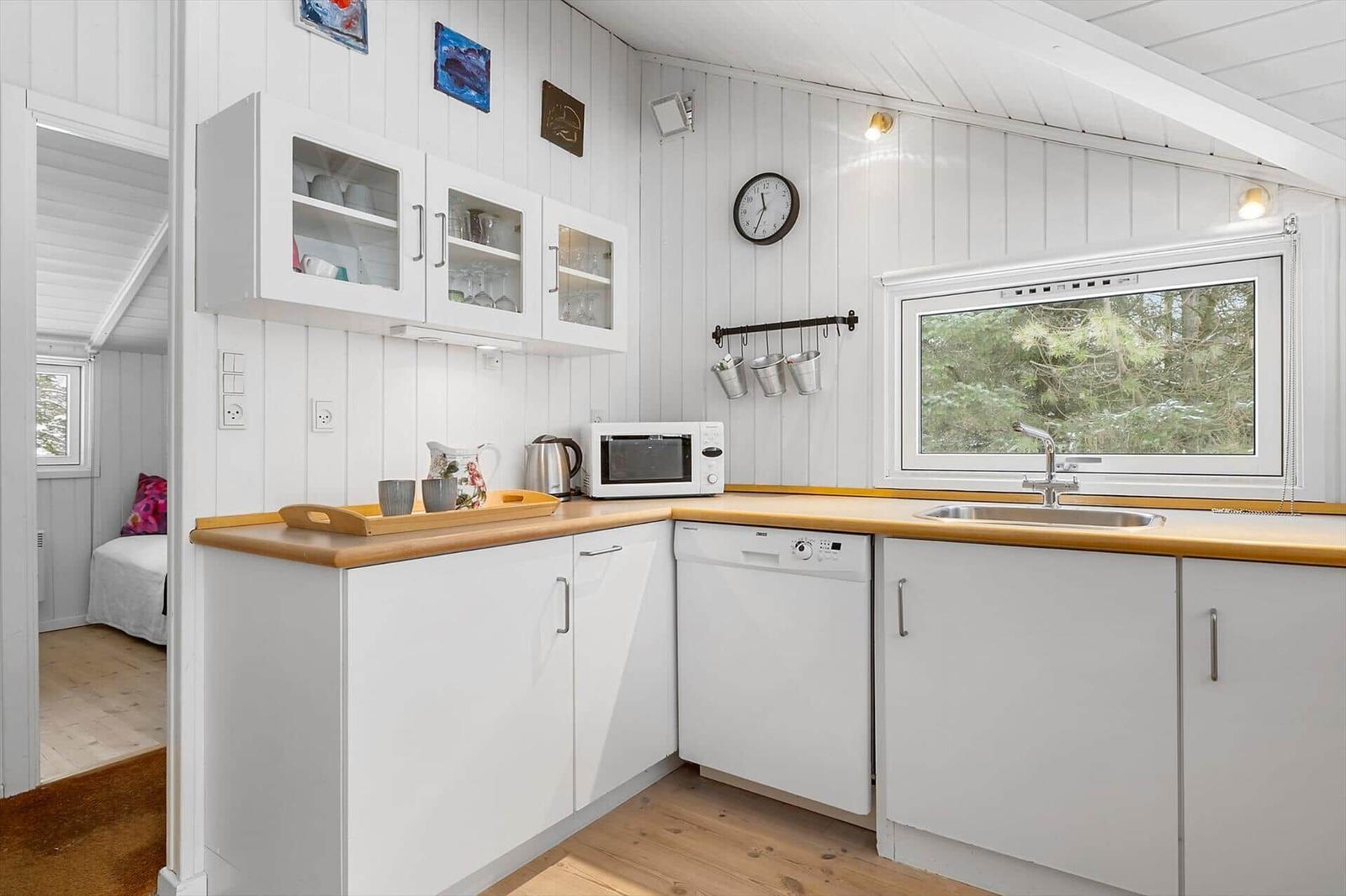 Kitchen with white cabinets, wooden countertops, and view of forest.