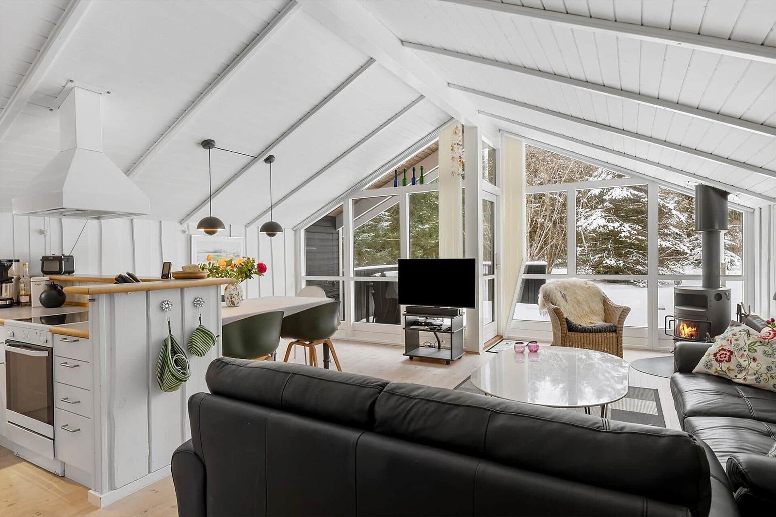 Living kitchen with dining area and fireplace. Large windows with snowy view.