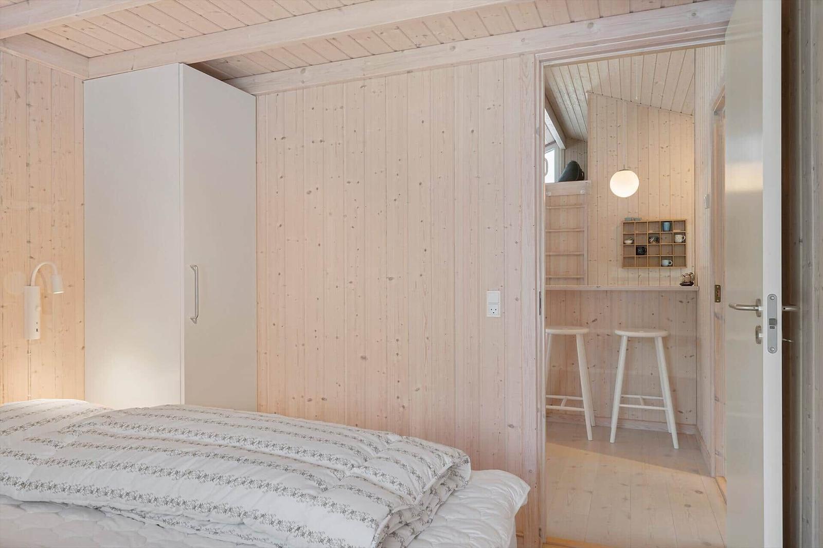 Bedroom with bed and wardrobe. Passage to small bar with stools.