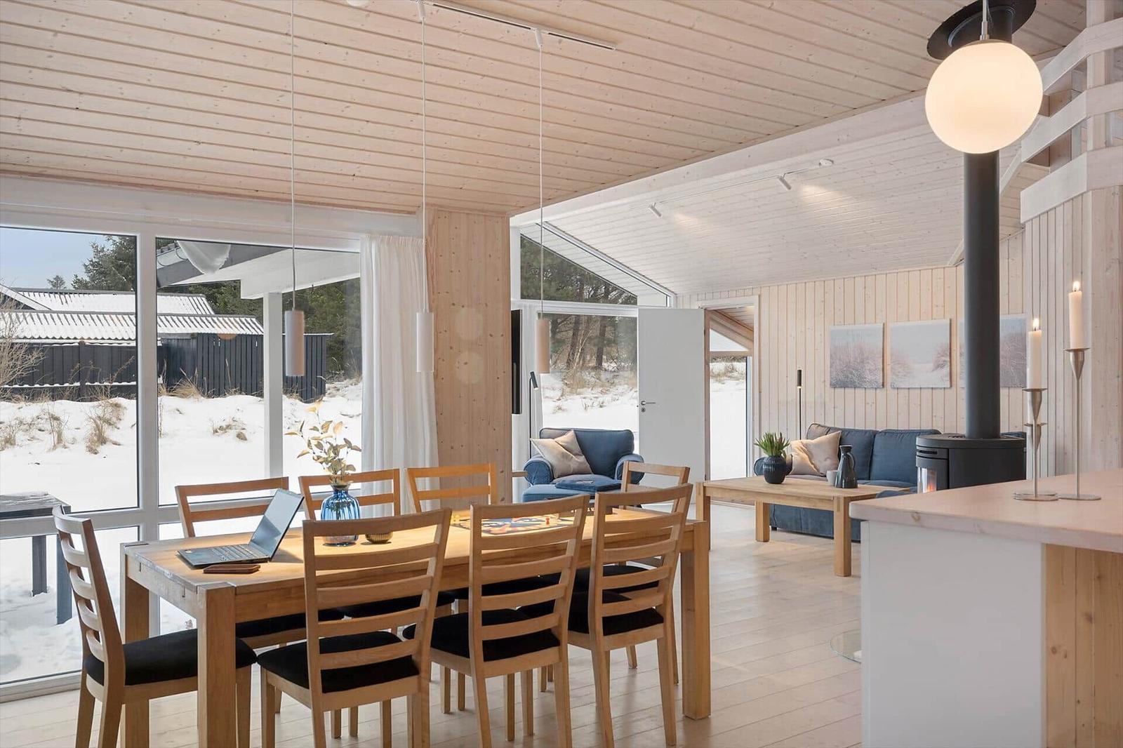 Dining area with wooden table and chairs, living area with sofa and stove