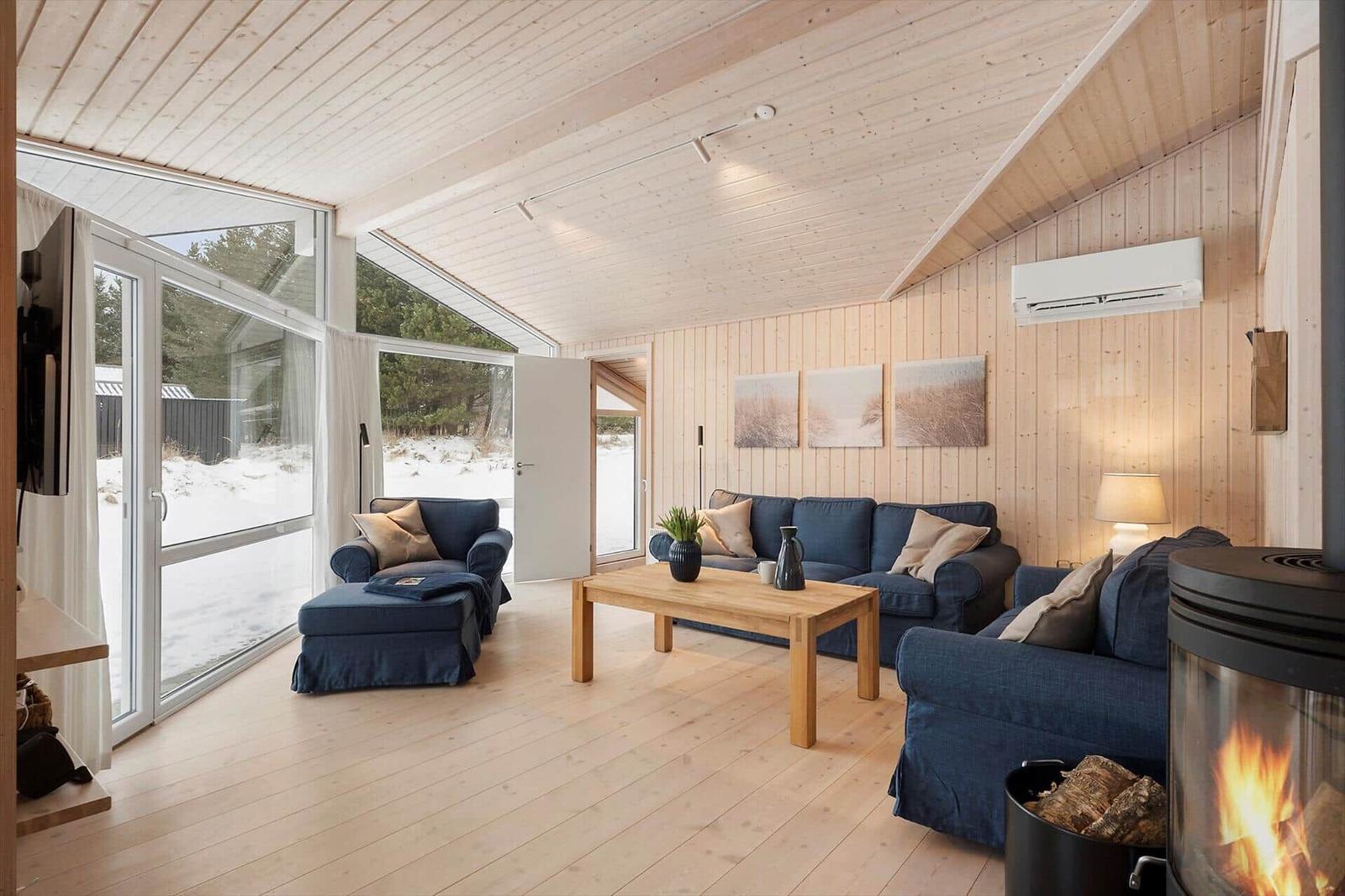 Living room with wooden ceiling, blue sofas, and fireplace