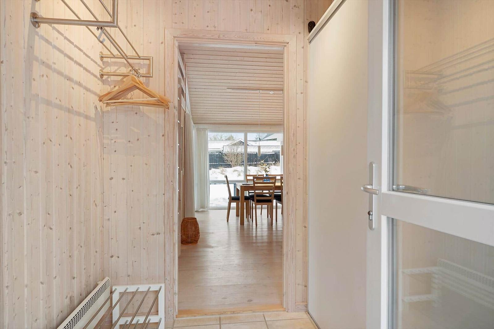 Hallway with coat rack and view into dining area with table and chairs.