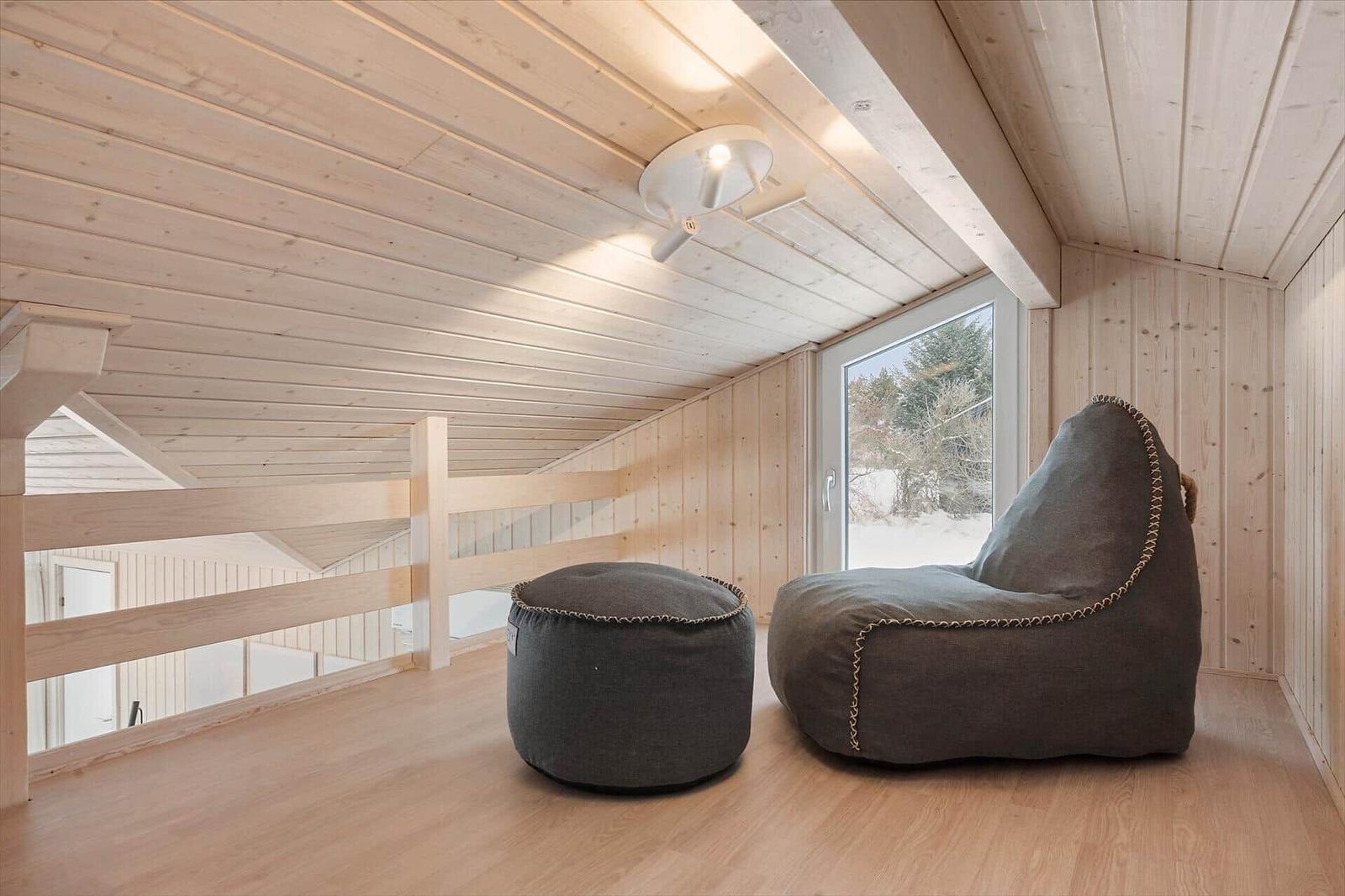 Attic room with wooden ceiling, gray bean bag, and window view