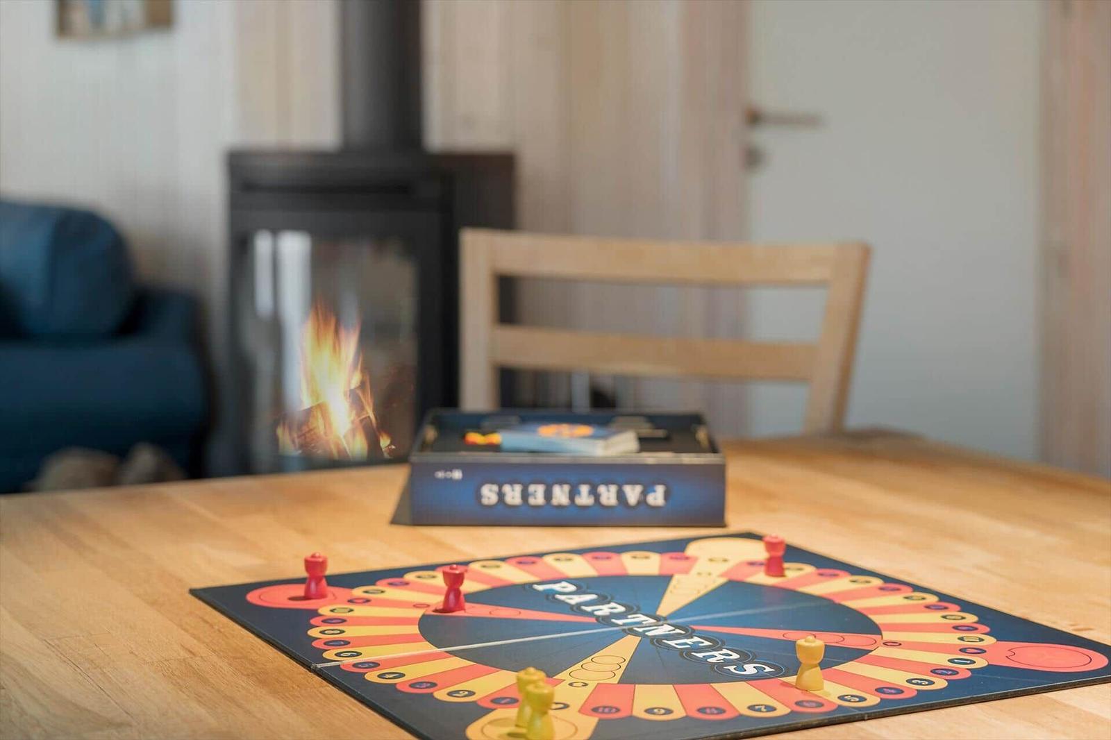 A board game on a wooden table in front of a fireplace with burning fire.