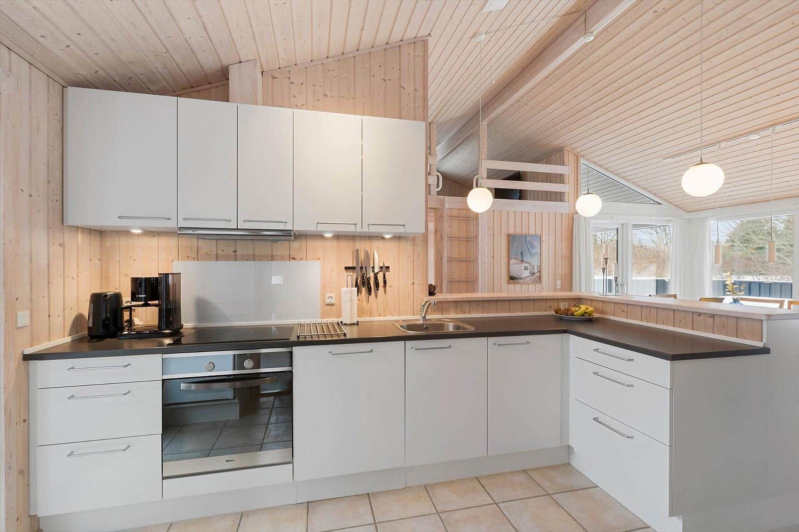 Kitchen with white cabinets, dark countertop, and wood paneling.