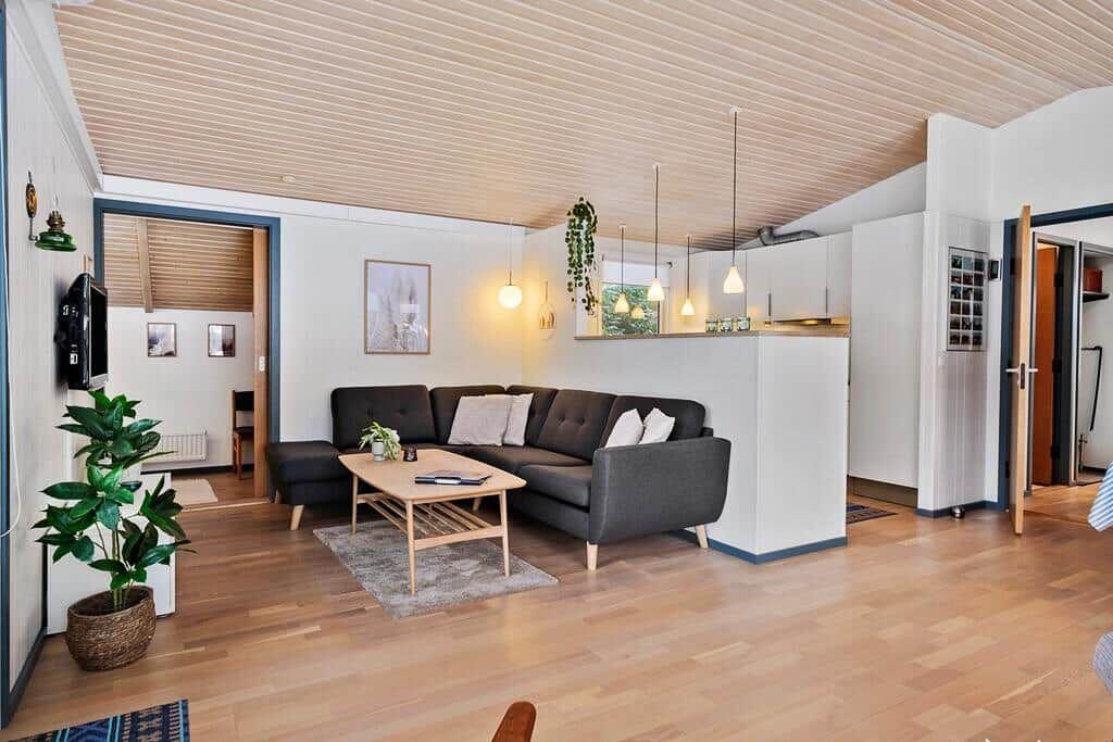 Living room with sofa, table, and hardwood floor. Kitchen and bedroom are visible.