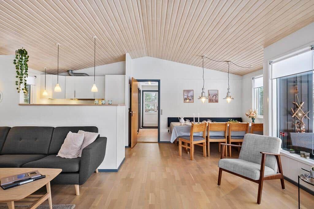 Living and dining area with wooden ceiling, sofa, table and chairs.