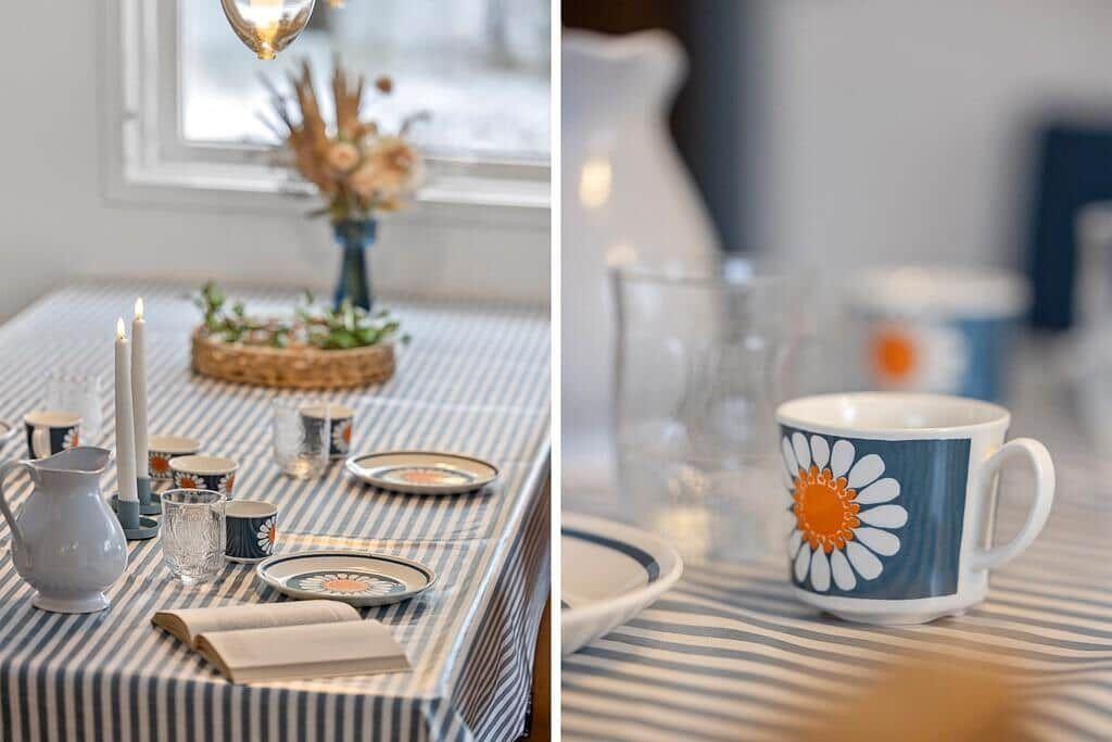 Table set with plates, mug, and candles. Vase with flowers and open book.