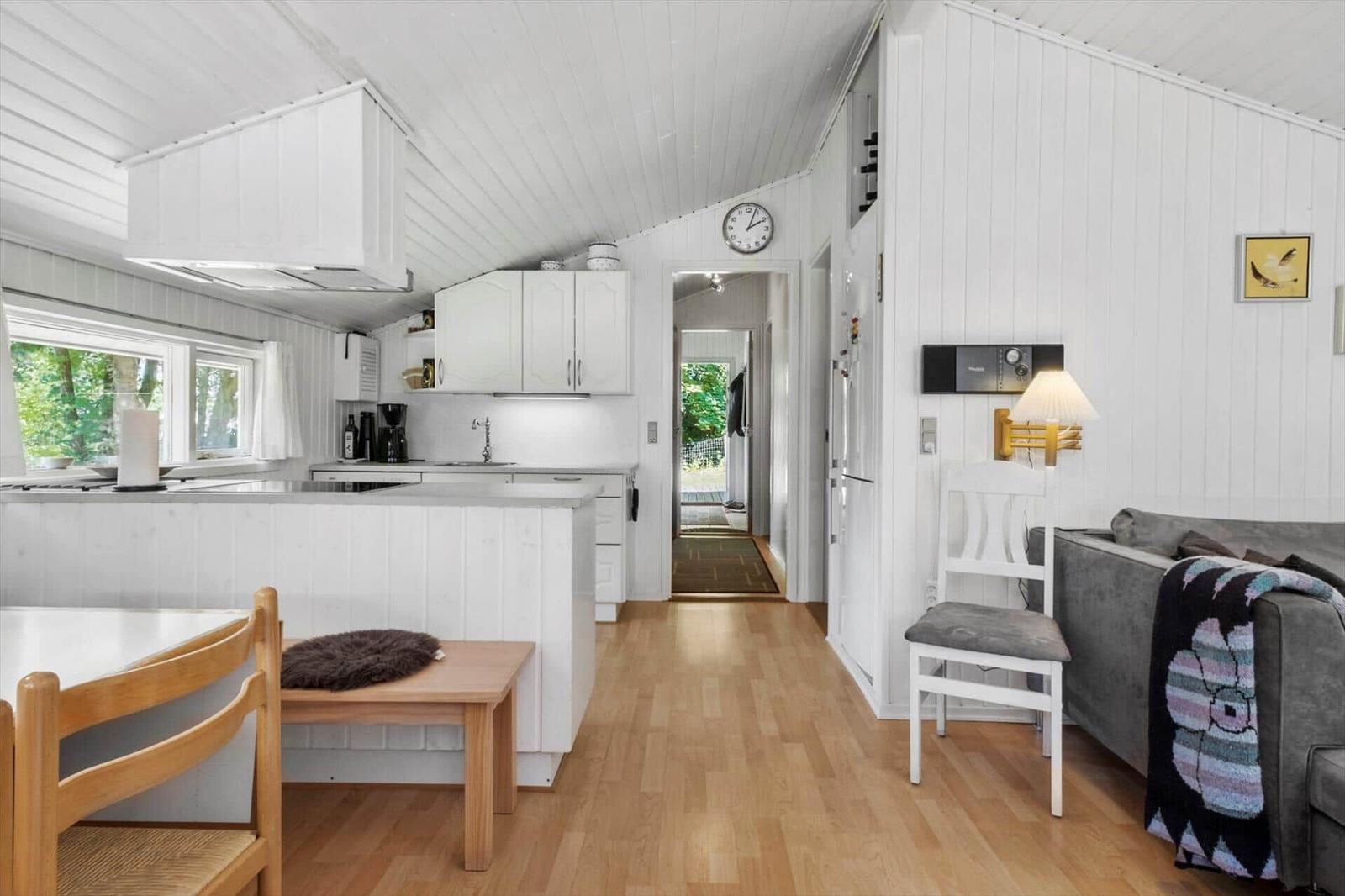 Kitchen with dining area and living area in a bright room with wooden floor and white walls.