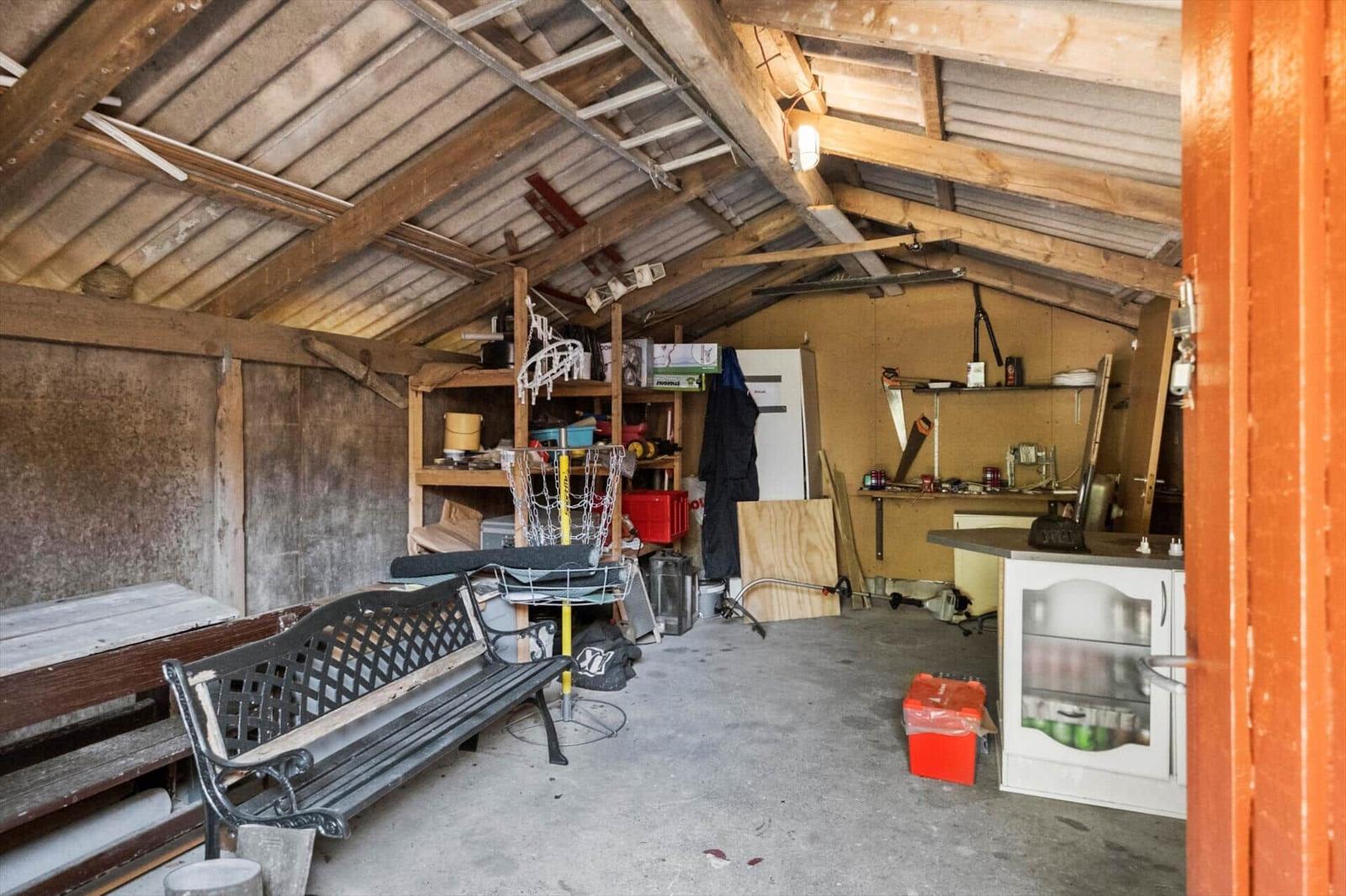 Vaulted space with wooden ceiling, workbench, chair, and kitchenette.