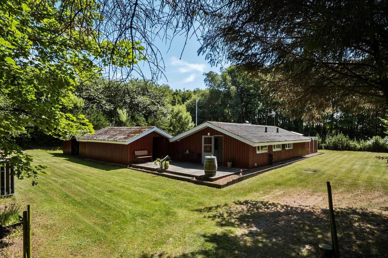 Red wooden house with terrace and garden under trees