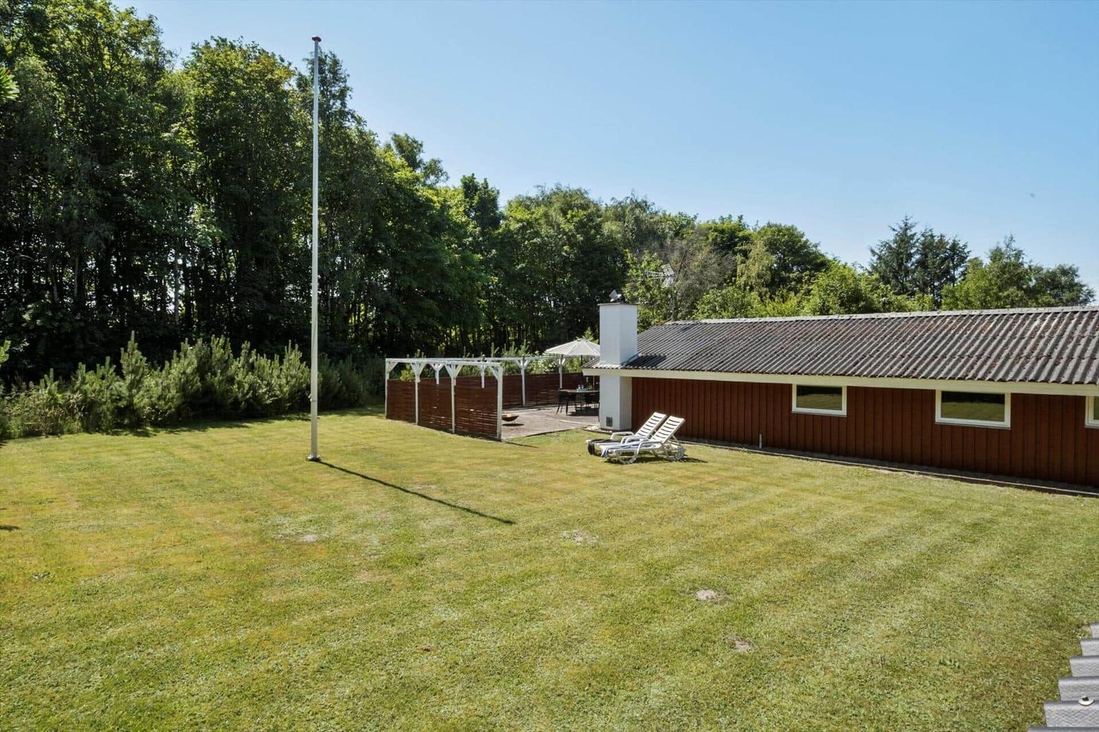 House with garden, sun loungers, and terrace under trees.