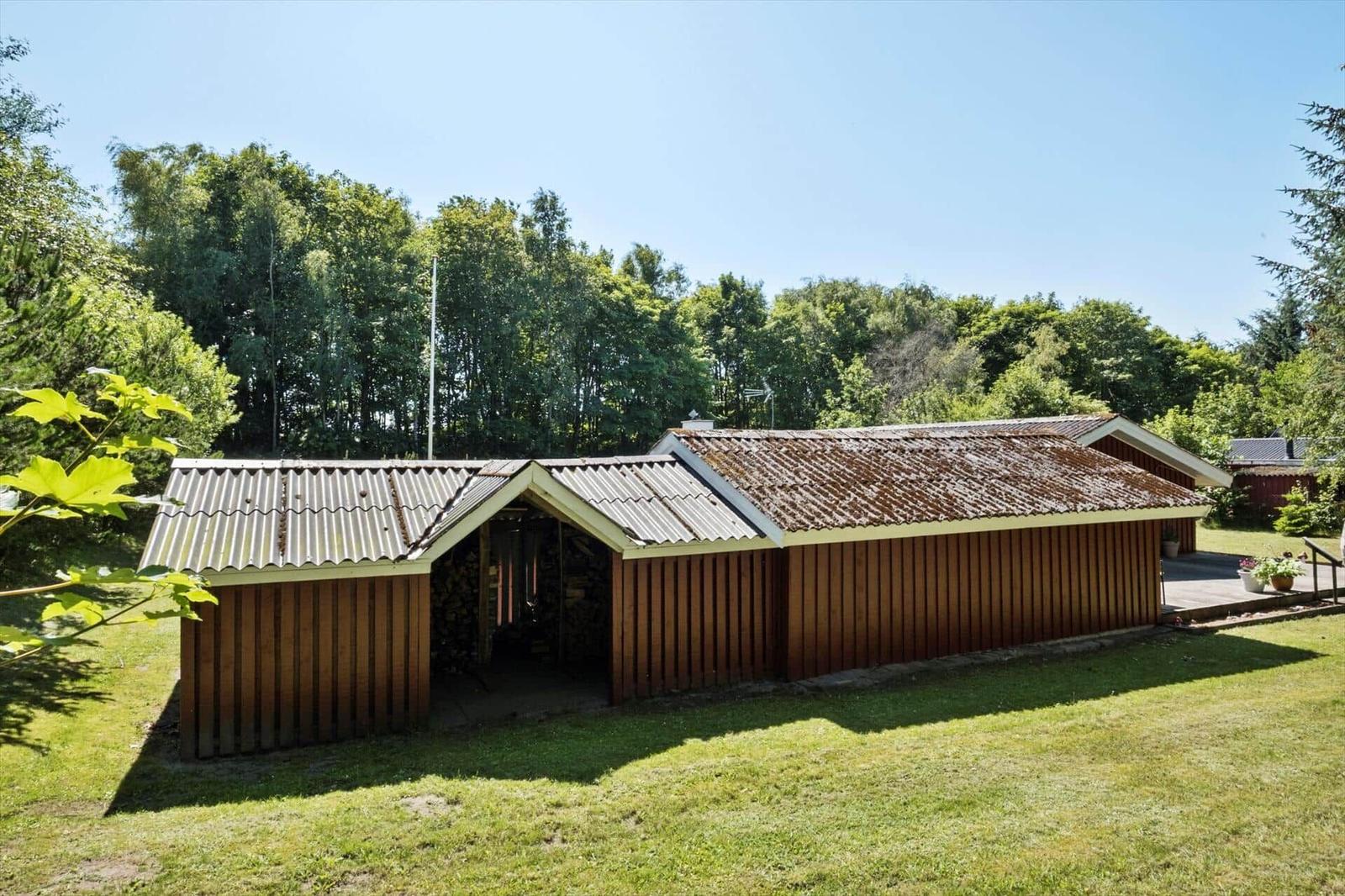 Wooden building with roof and woodpile in the garden