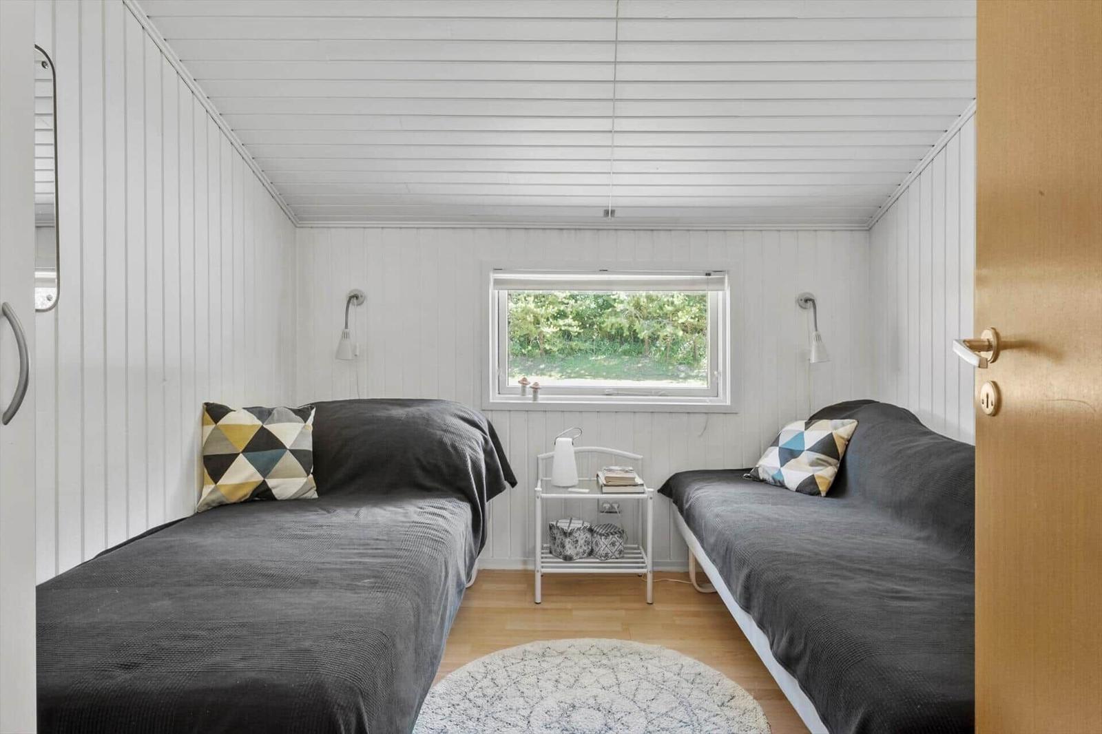 Two sleeping areas with dark bed covers and colorful pillows.