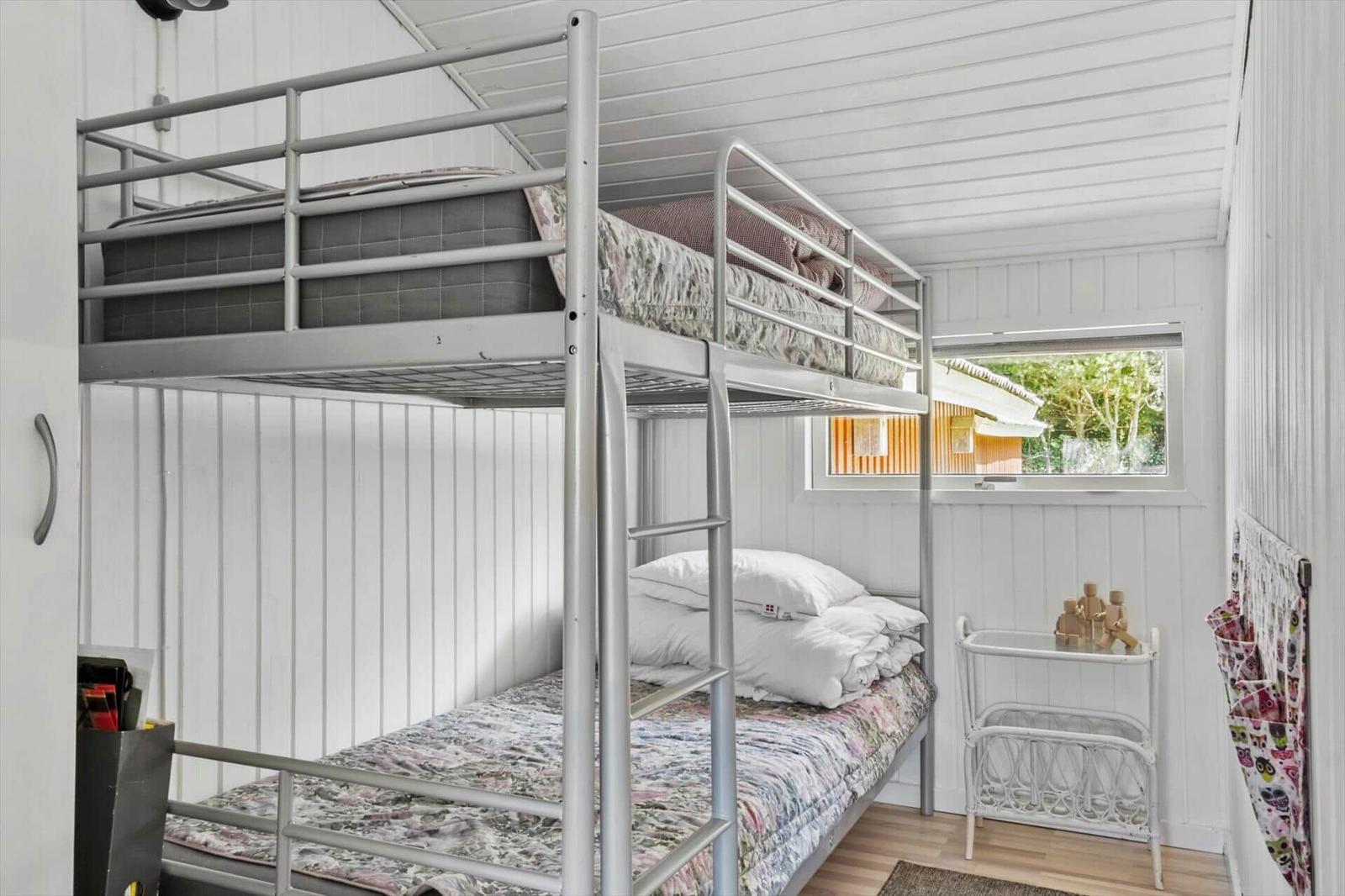 Room with bunk bed, window and small table.