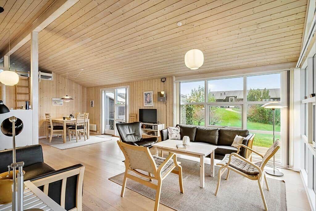 Living room with dining area, sofa, chairs, and large windows.