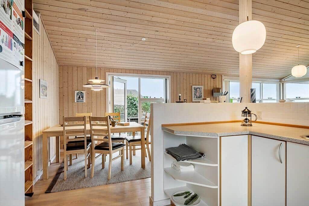 Kitchen with dining area, wood walls, and glass doors. Countertop, chairs, and table visible.