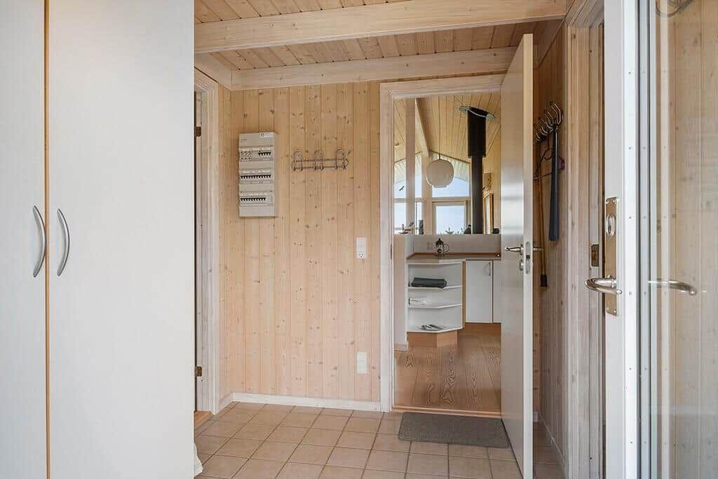 Entrance area with wooden wall and door to bathroom.