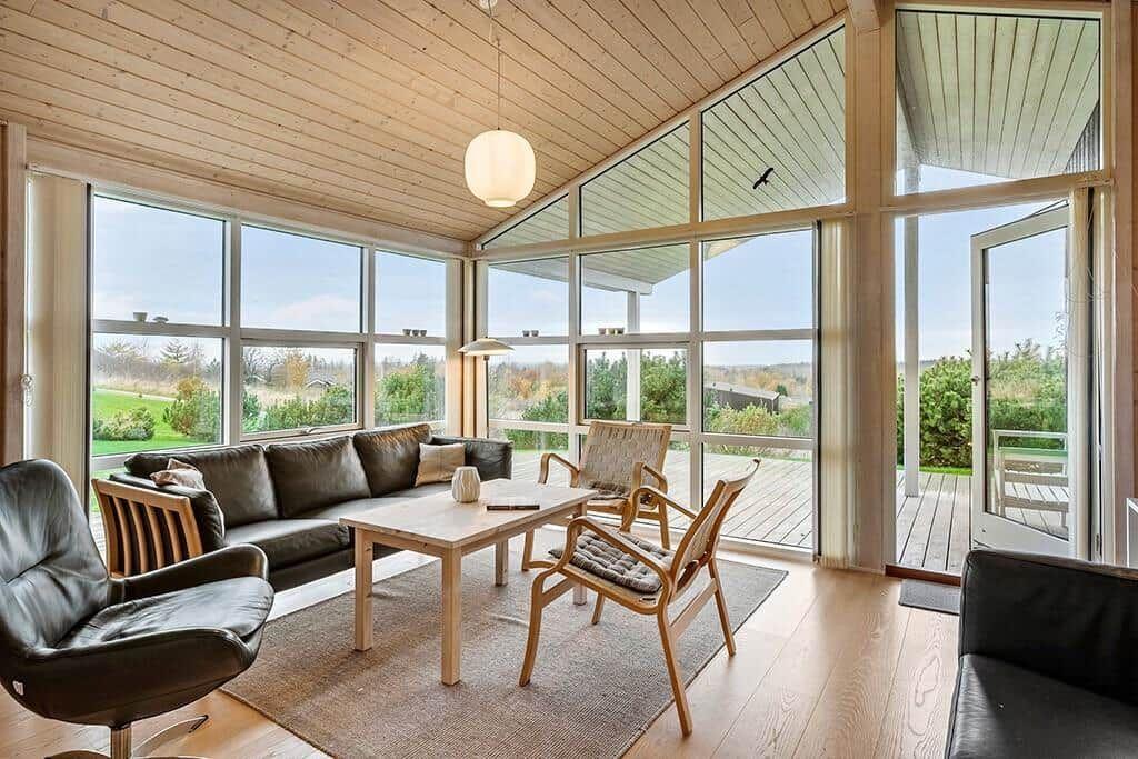 Living room with wooden ceiling, large windows, and view of the terrace.