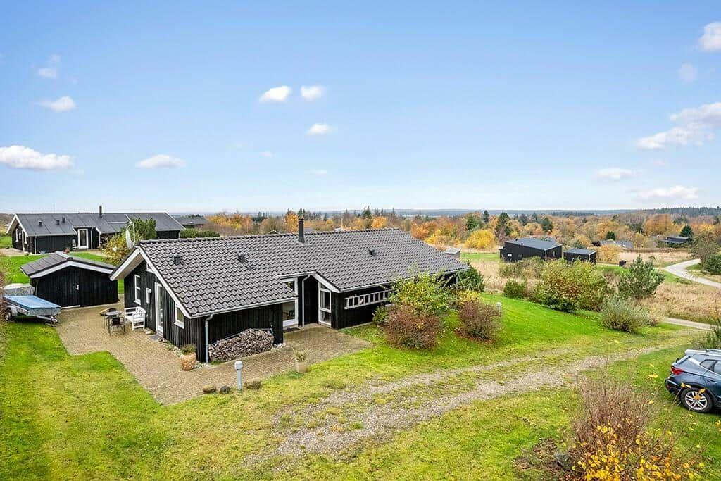 Black house with terrace and garden. View of forest and fields.