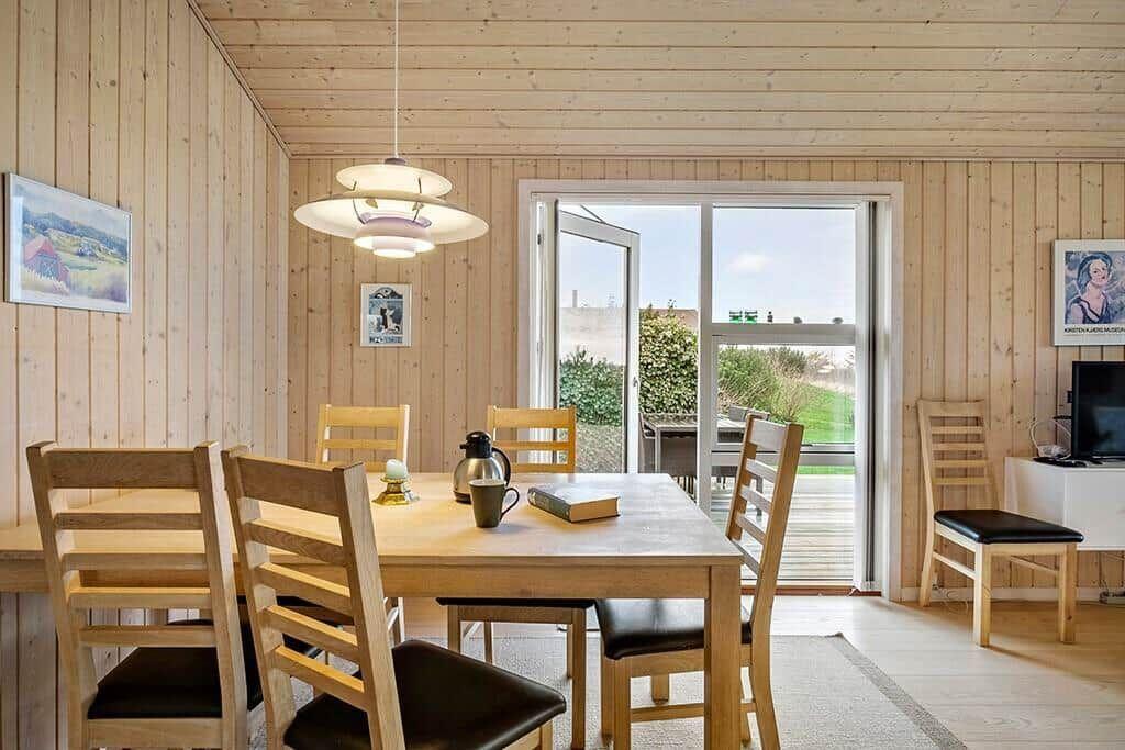 Dining room with wooden table, chairs, and view of balcony.