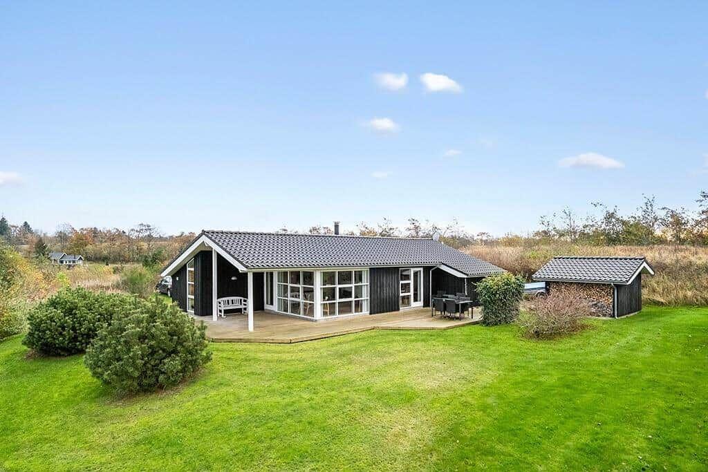 Modern wooden house with terrace, garden, and shed. Clear view of the field.